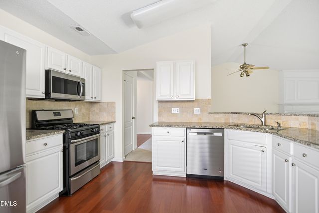 a kitchen with stainless steel appliances a sink cabinets and wooden floor