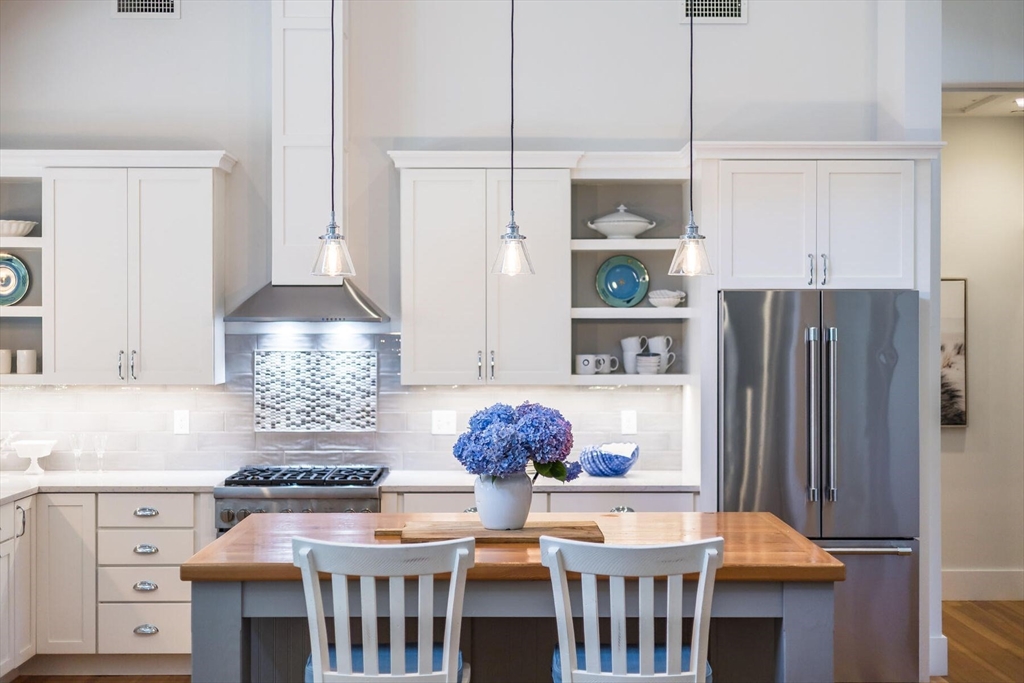950 Massasoit Road, Unit 3 Eastham, MA 02642 - Photo 17 of 42 a kitchen with stainless steel appliances granite countertop a stove a refrigerator a dining table and chairs with wooden floor