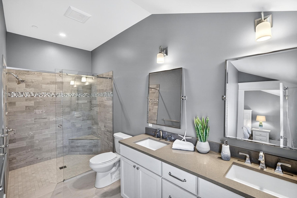 950 Massasoit Road, Unit 3 Eastham, MA 02642 - Photo 32 of 42 a bathroom with a granite countertop sink a toilet a mirror a bathtub and shower