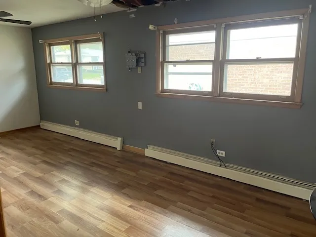 an empty room with wooden floor and windows