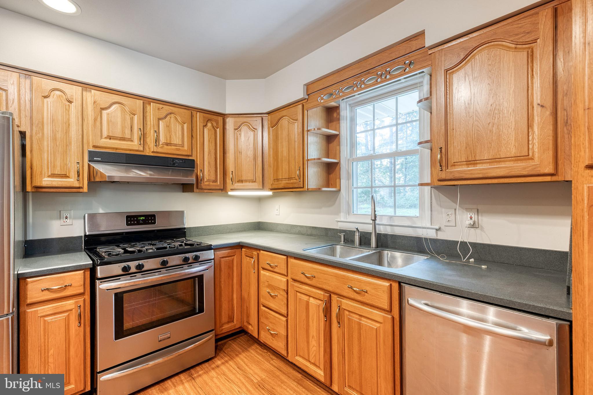 1022 Roxleigh Road Towson, MD 21286 - Photo 16 of 36 a kitchen with granite countertop a sink stainless steel appliances wooden cabinets and a window