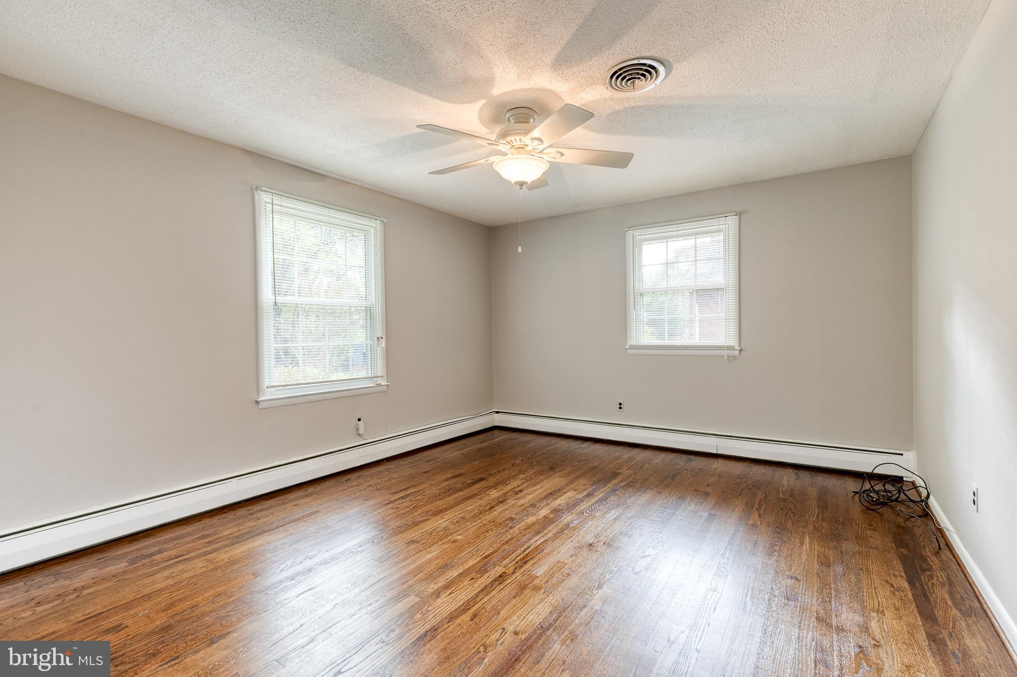 1022 Roxleigh Road Towson, MD 21286 - Photo 18 of 36 an empty room with wooden floor chandelier fan and windows