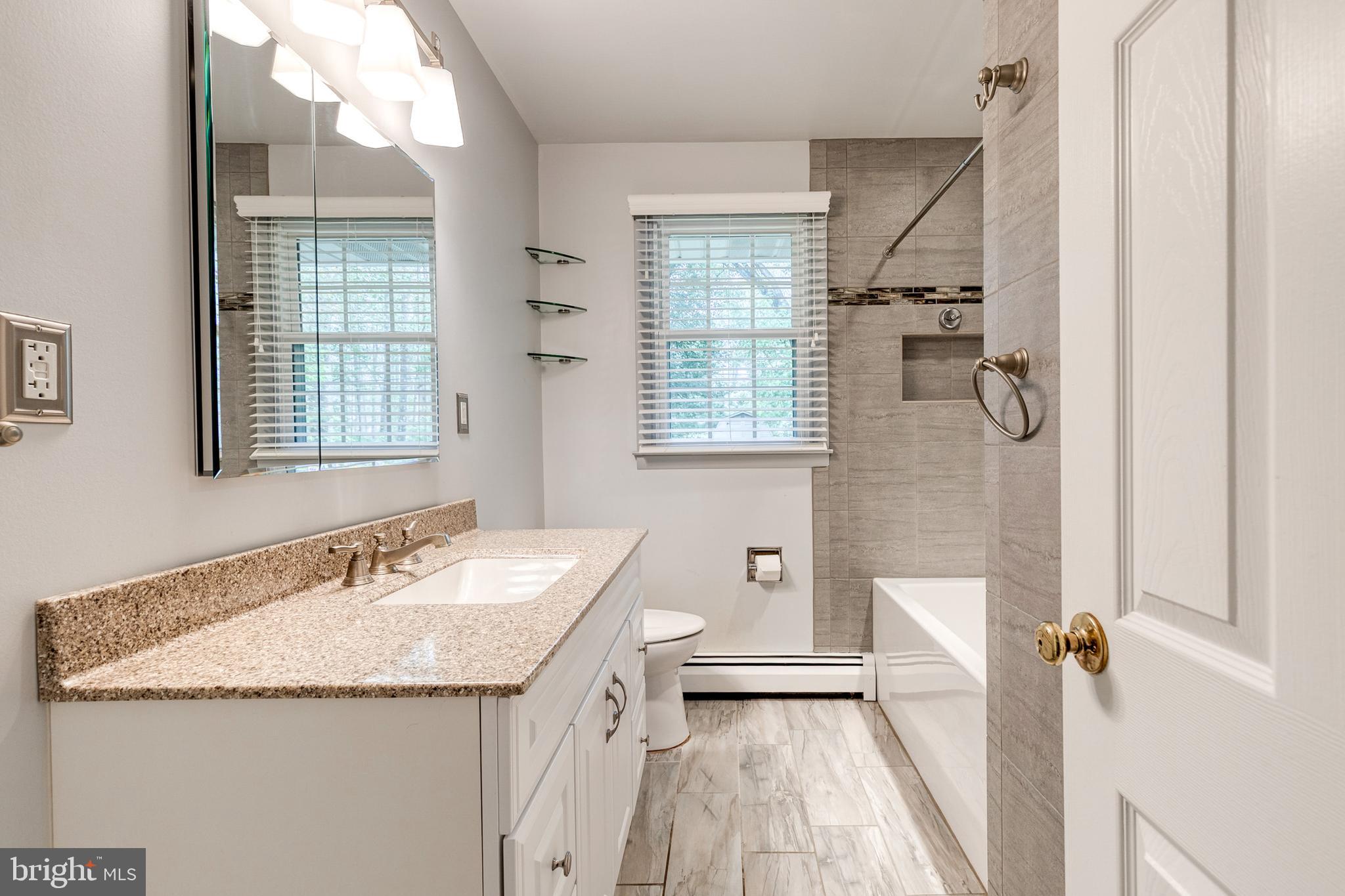 1022 Roxleigh Road Towson, MD 21286 - Photo 23 of 36 a bathroom with a granite countertop sink mirror and a bathtub