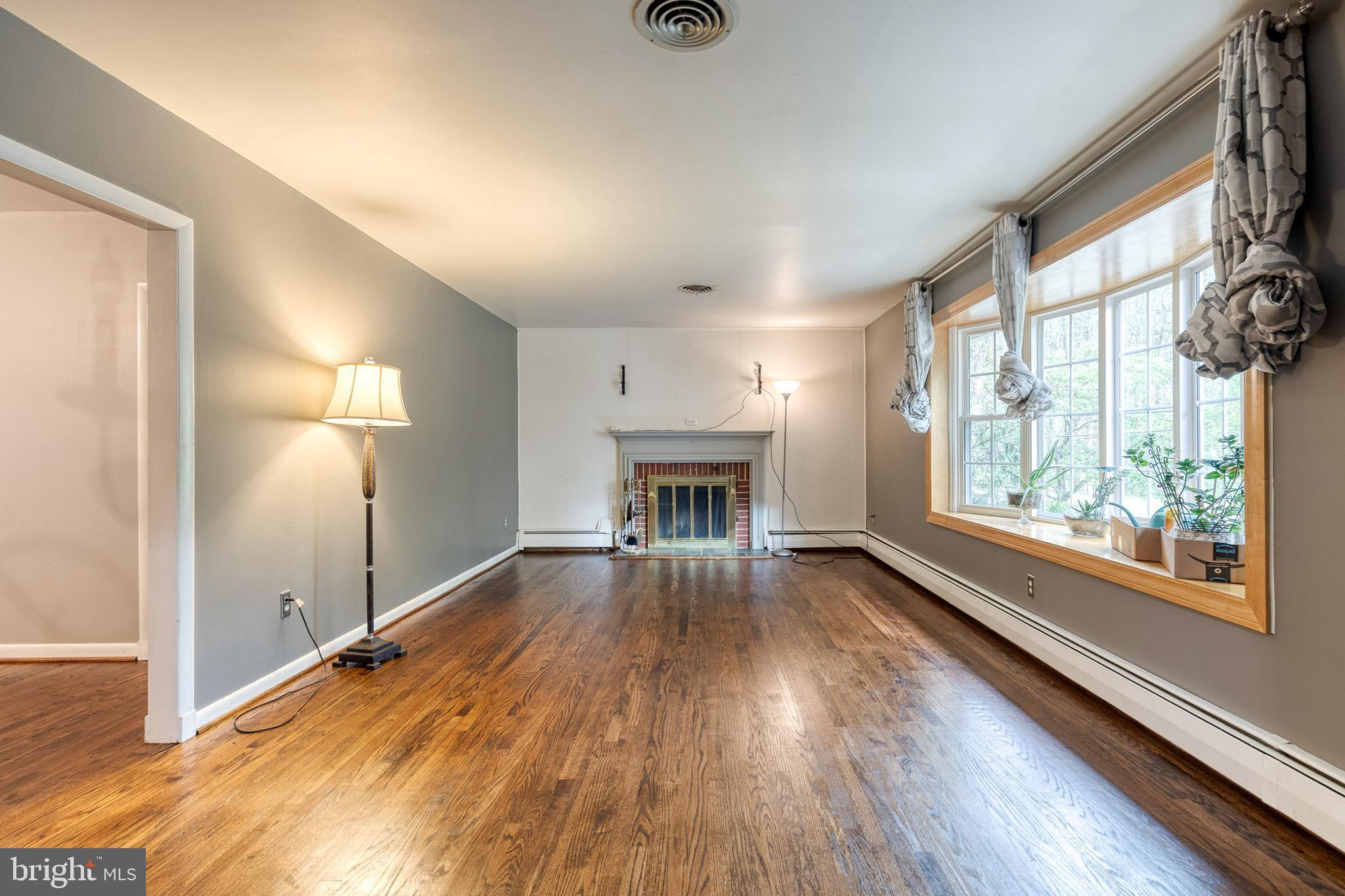 1022 Roxleigh Road Towson, MD 21286 - Photo 5 of 36 an empty room with wooden floor fireplace and windows