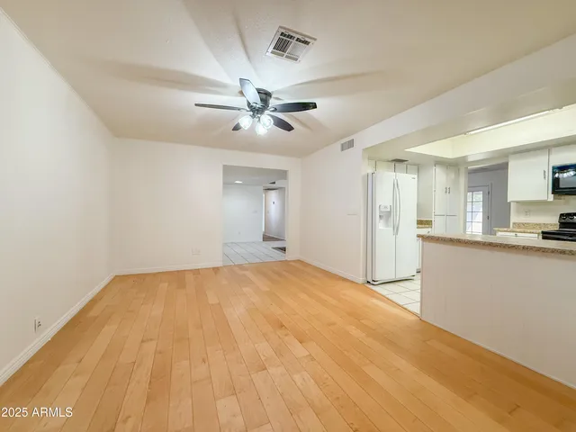 a view of an empty room with window and a kitchen