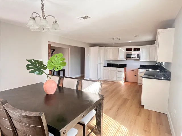 a kitchen with stainless steel appliances granite countertop a stove a refrigerator a sink a dining table and chairs with wooden floor