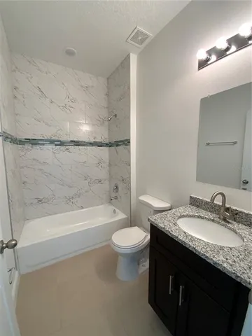 a bathroom with a granite countertop sink a toilet a mirror and bathtub