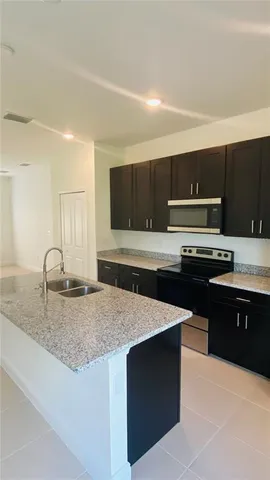 a kitchen with kitchen island granite countertop a sink dishwasher stove and oven with cabinets