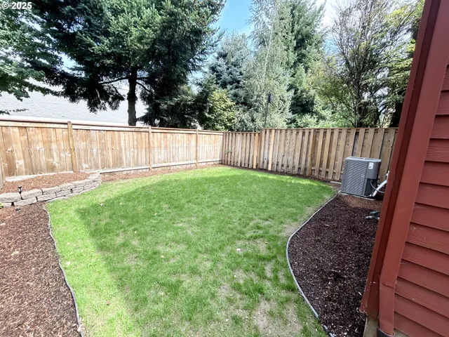 a view of a backyard with a large tree and wooden fence