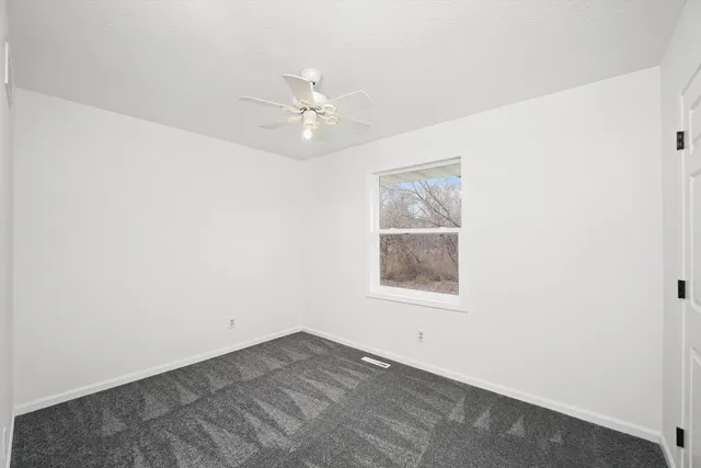 an empty room with a window and ceiling fan