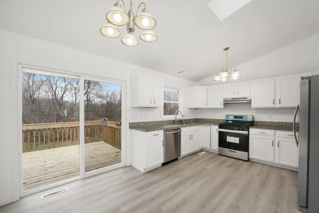 a large kitchen with cabinets wooden floor and stainless steel appliances