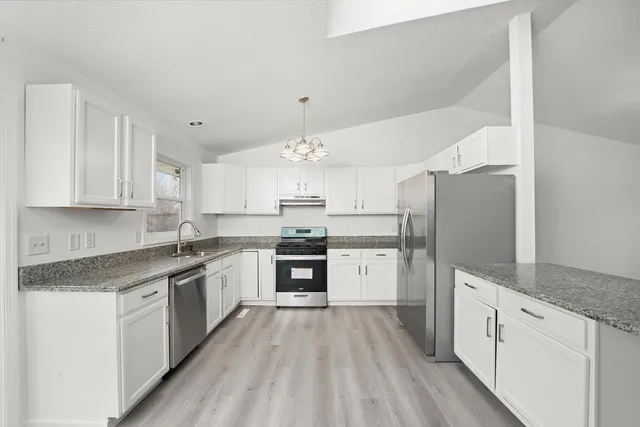 a large kitchen with stainless steel appliances granite countertop a lot of counter space and wooden floors