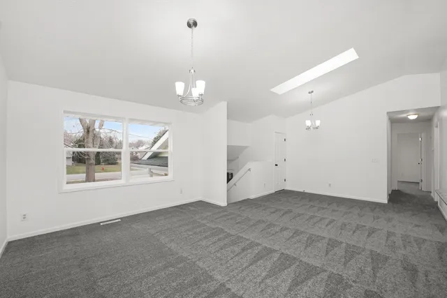 an empty room with chandelier and windows