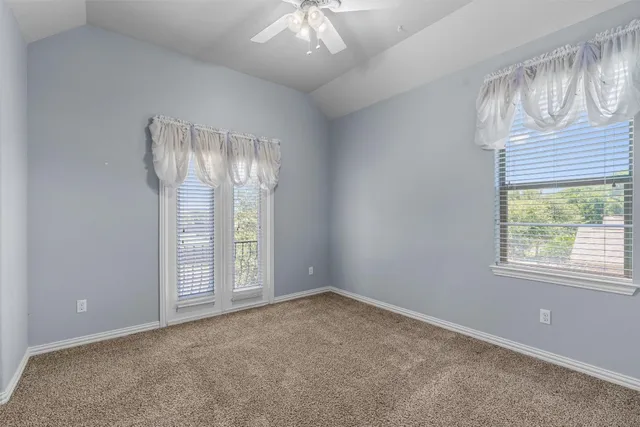 an empty room with windows and way to kitchen