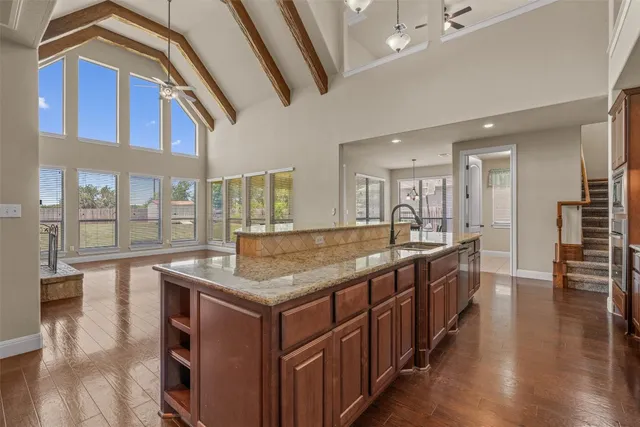 a spacious bathroom with a granite countertop sink a large mirror and a wooden floor