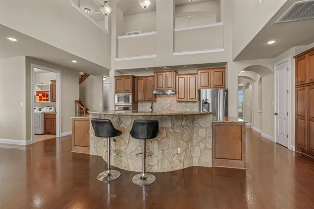 a kitchen with stainless steel appliances kitchen island granite countertop a table chairs and a refrigerator