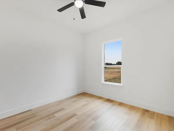 a view of an empty room with wooden floor fireplace and a window