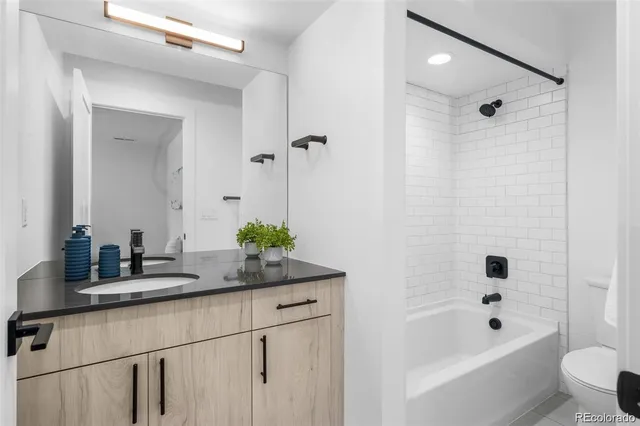 a bathroom with a granite countertop sink a toilet a mirror a vanity and shower