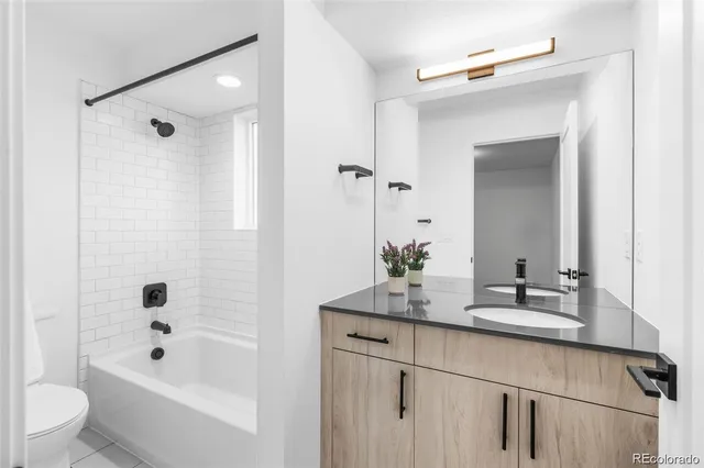 a bathroom with a bathtub shower sink vanity and toilet