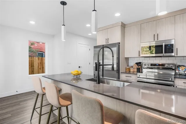 a kitchen with stainless steel appliances granite countertop a sink a stove and a wooden floors