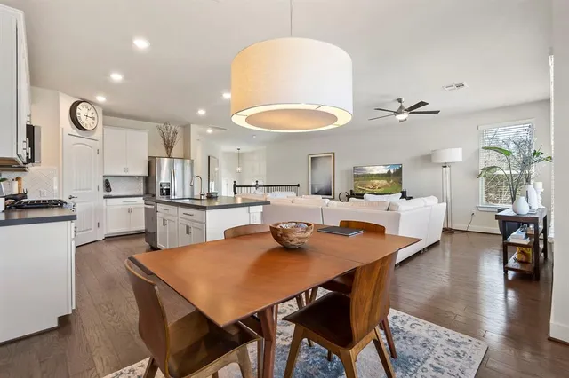 a living room with stainless steel appliances furniture dining table and wooden floor