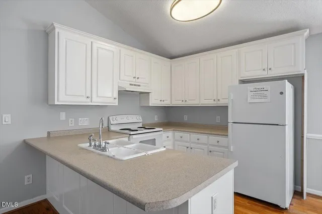 a kitchen with a sink a stove and white cabinets