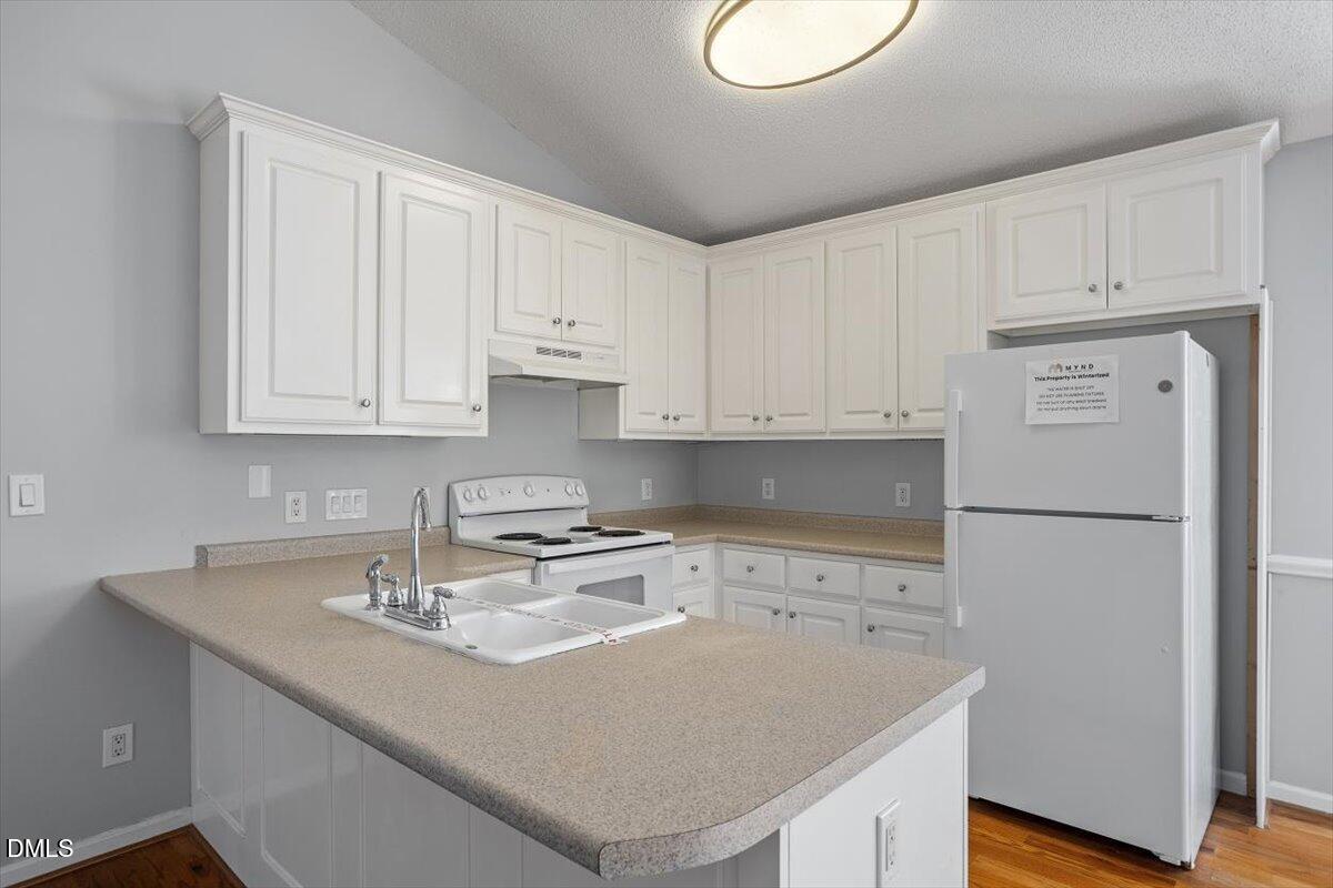 1084 McLemore Road Clayton, NC 27520 - Photo 14 of 34 a kitchen with a sink a stove and white cabinets