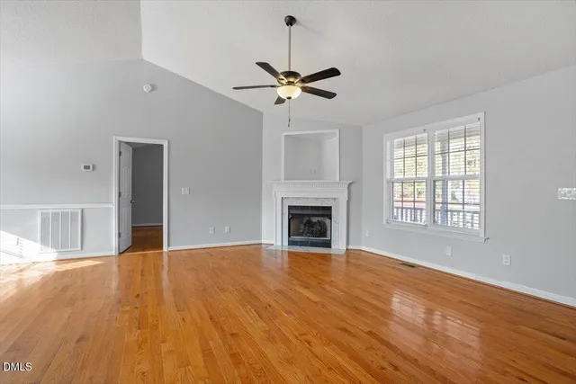 a view of empty room with wooden floor fireplace and window