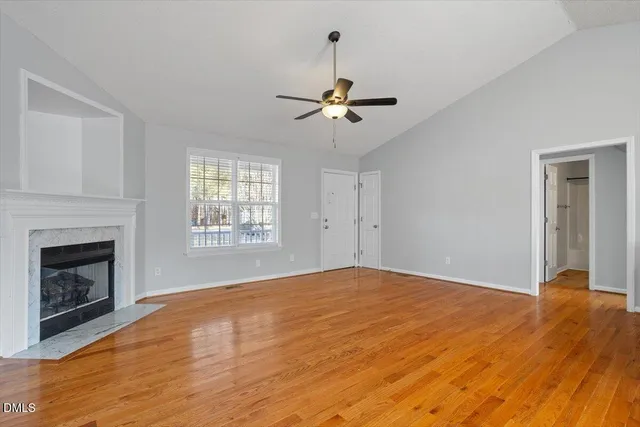 a view of empty room with fireplace and wooden floor