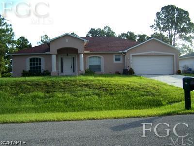 1569 Meadow Road Lehigh Acres, FL 33976 - Photo 1 of 19 a front view of a house with yard and green space