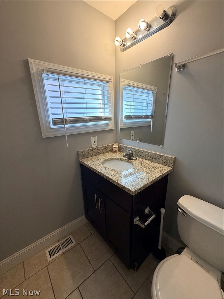 2017 Random Road Cleveland, OH 44106 - Photo 16 of 20 Modern bathroom featuring a granite-topped vanity with dual sink configuration, dark cabinetry with chrome hardware, and a large framed mirror with integrated lighting