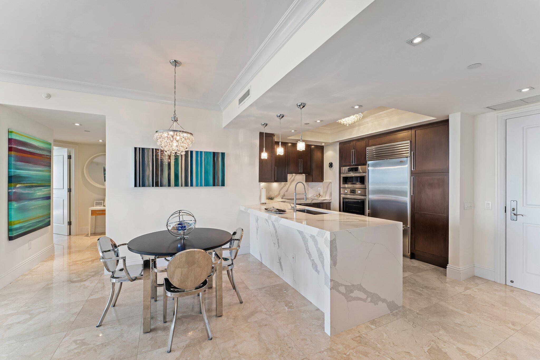 2700 North Ocean Drive, Unit 304B Singer Island, FL 33404 - Photo 49 of 91 a kitchen with stainless steel appliances kitchen island granite countertop a table chairs and a refrigerator