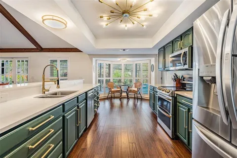 a kitchen with stainless steel appliances granite countertop a stove top oven a refrigerator a dining table and chairs with wooden floor