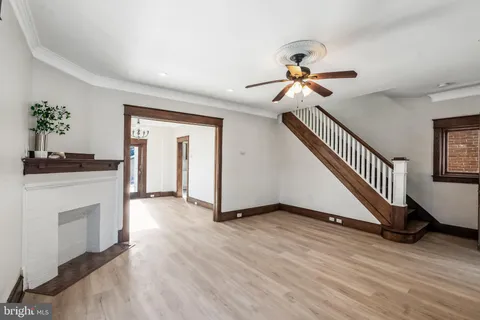a view of an empty room with chandelier fan and wooden floor