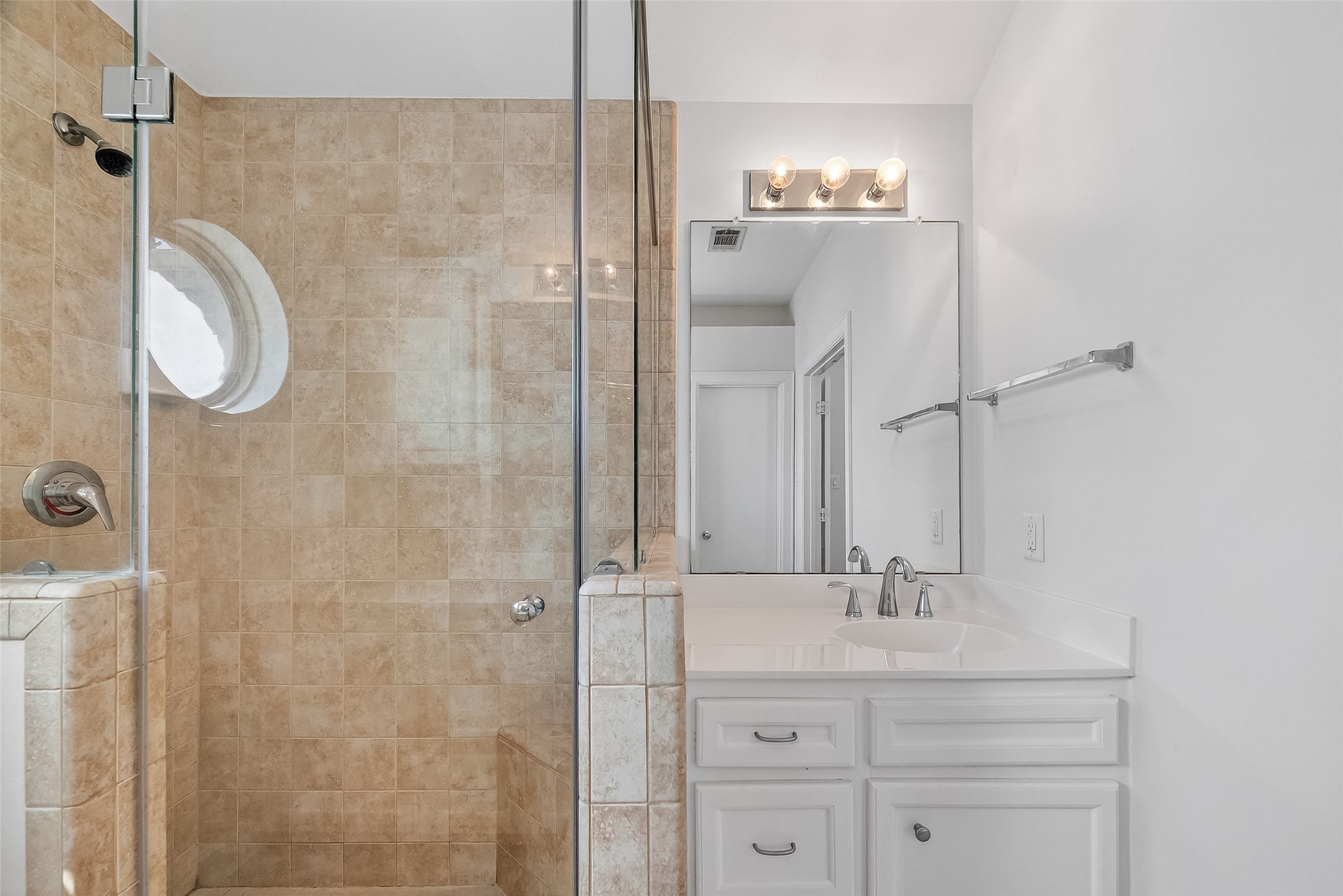 5951 S Loop East, Unit 47 Houston, TX 77033 - Photo 22 of 37 Primary bathroom features a spacious walk-in shower with a modern glass door. The vanity offers ample storage with white cabinets and a sleek countertop. The large mirror and light fixture above provide excellent lighting, enhancing the room's bright and clean aesthetic.