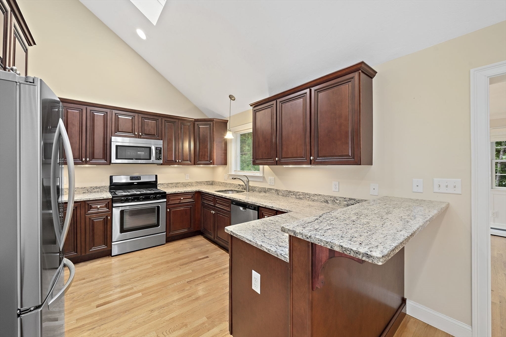 14 Sugar Maple Circle, Unit 14 Hanover, MA 02339 - Photo 3 of 38 a kitchen with stainless steel appliances granite countertop a stove top oven a sink dishwasher a refrigerator and a microwave oven with wooden cabinets