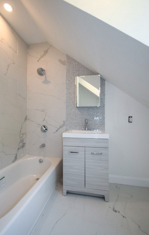 32 Cedar Street, Unit RIGHT Boston, MA 02126 - Photo 6 of 11 a bathroom with a bathtub sink vanity and mirror