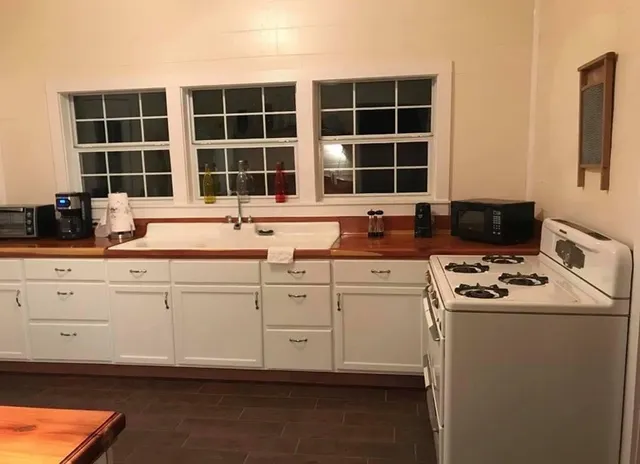 a kitchen with granite countertop white cabinets sink and with stainless steel appliances
