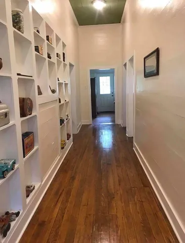 a view of a hallway with wooden floor and windows