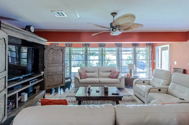 a living room with furniture a flat screen tv and a floor to ceiling window