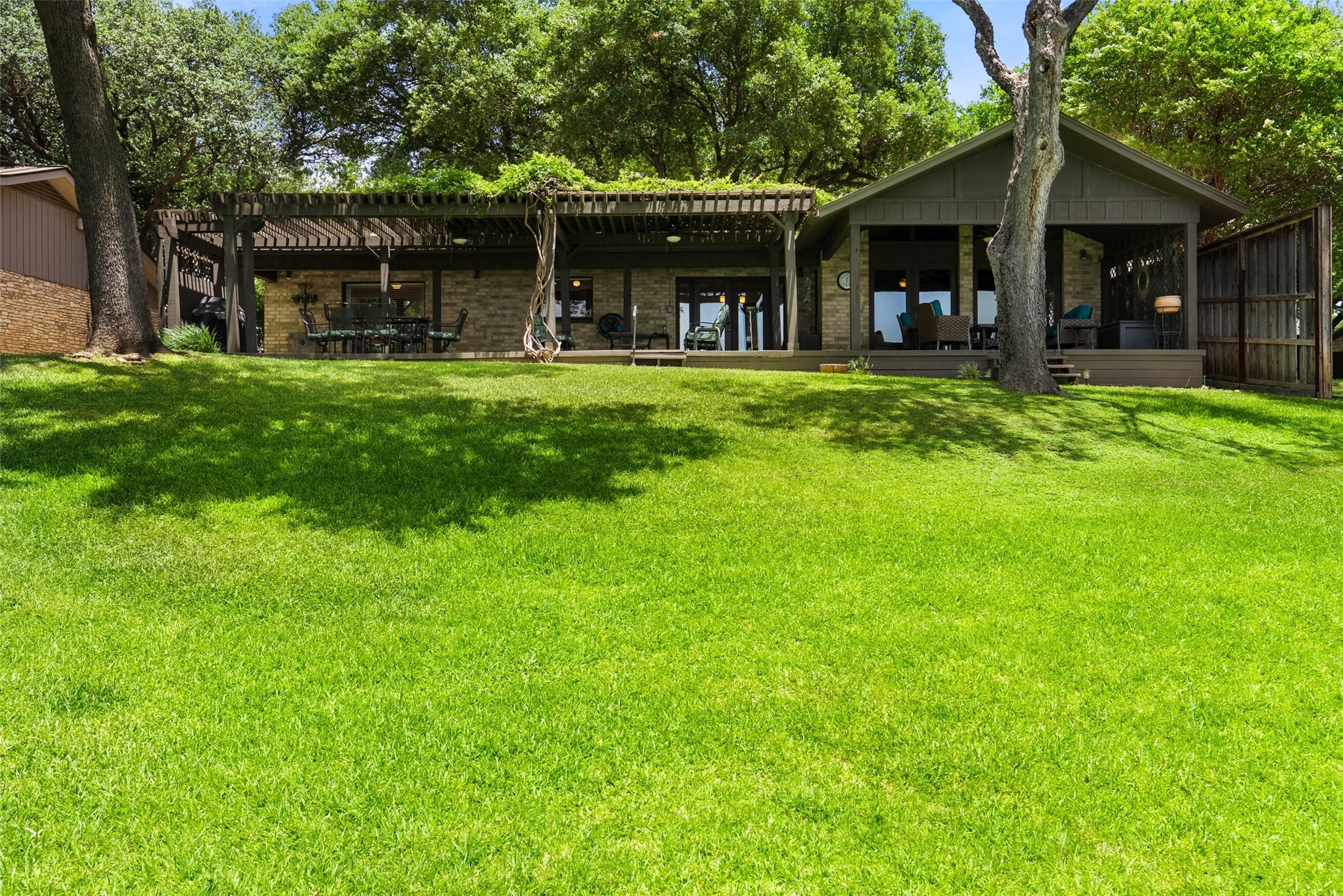 141 Perry Lane Kingsland, TX 78639 - Photo 2 of 40 A verdant lawn leads to a charming residence featuring a covered patio and a large pergola.