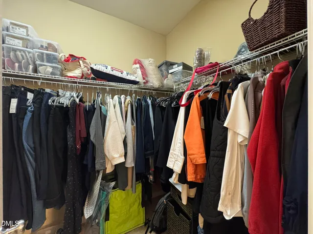 a view of walk in closet with clothes and shoes