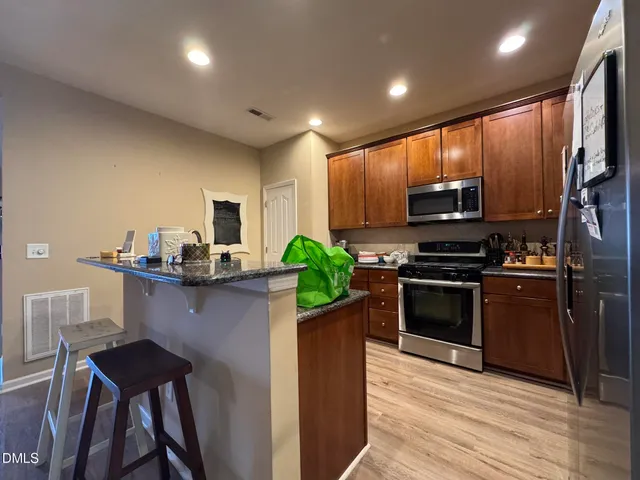 a kitchen with kitchen island granite countertop stainless steel appliances and wooden cabinets