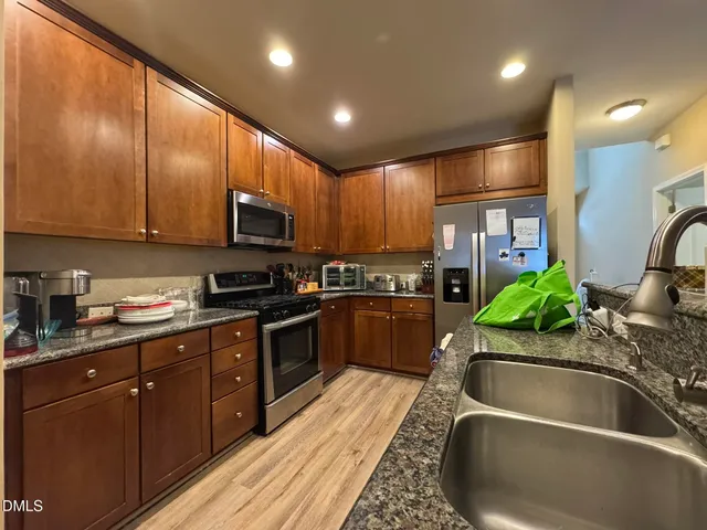 a kitchen with kitchen island granite countertop a sink stainless steel appliances and cabinets