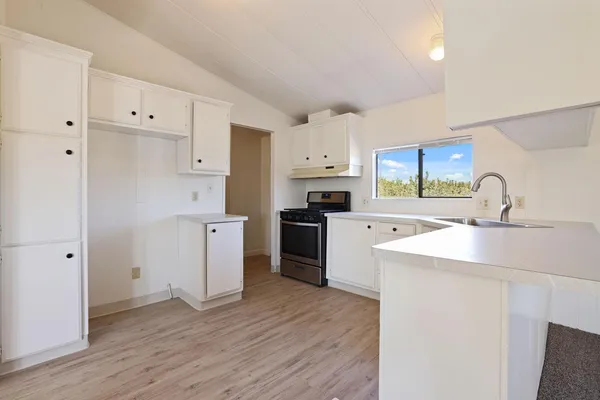 a kitchen with a sink a stove a refrigerator and white cabinets