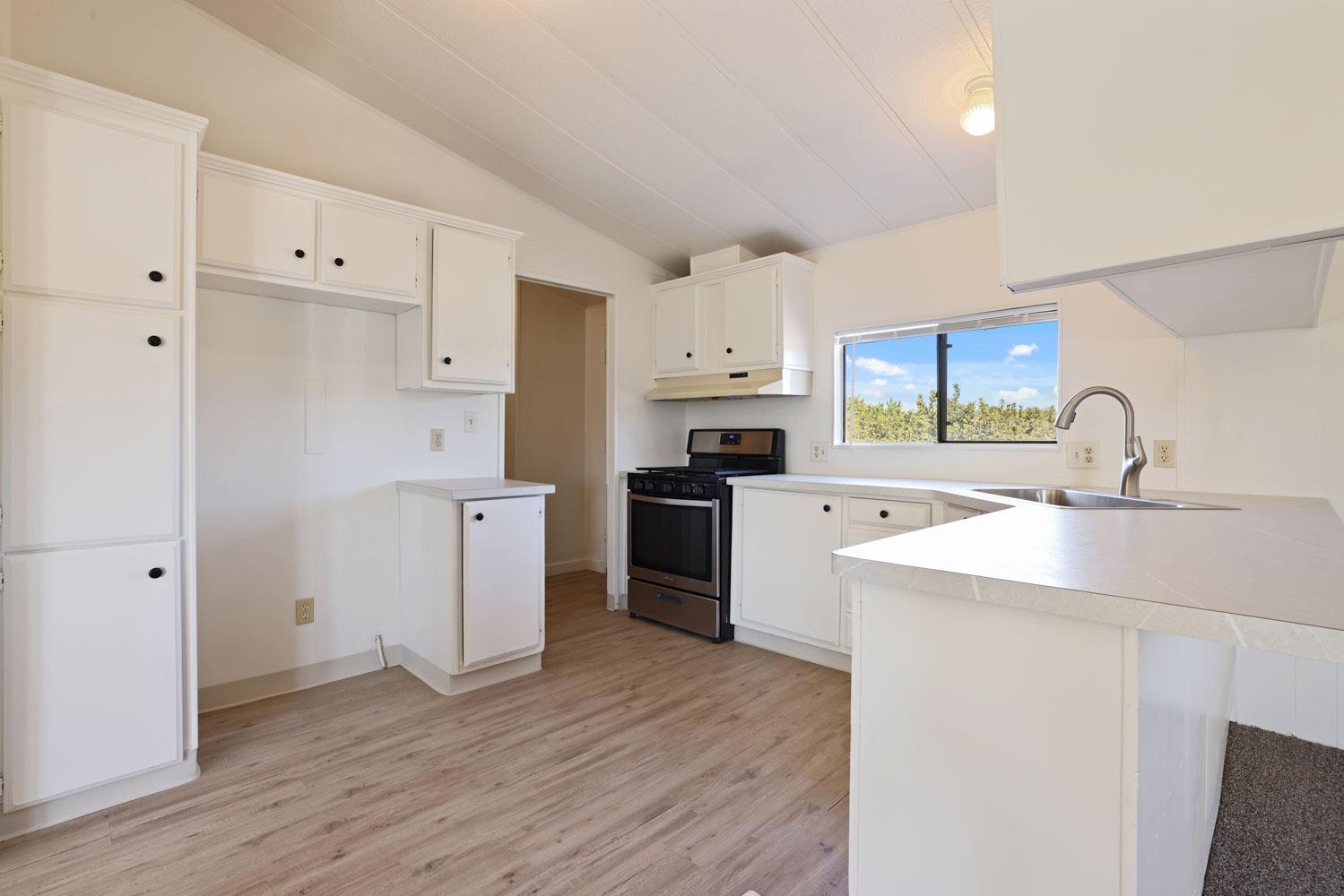 3443 Kansas Avenue Modesto, CA 95358 - Photo 25 of 45 a kitchen with a sink a stove a refrigerator and white cabinets