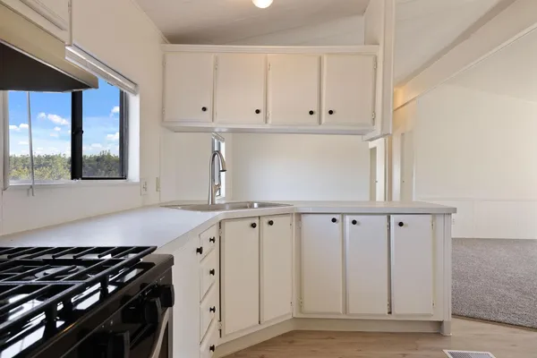 a kitchen with white cabinets and window