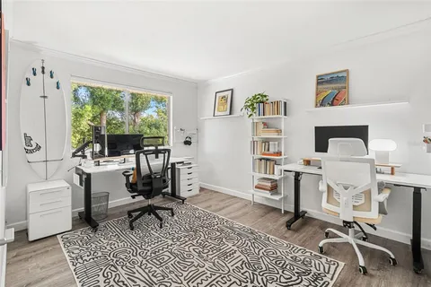 a work room with furniture a rug and a window