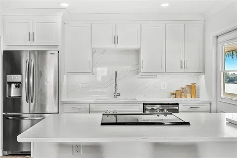 a kitchen with white cabinets and refrigerator