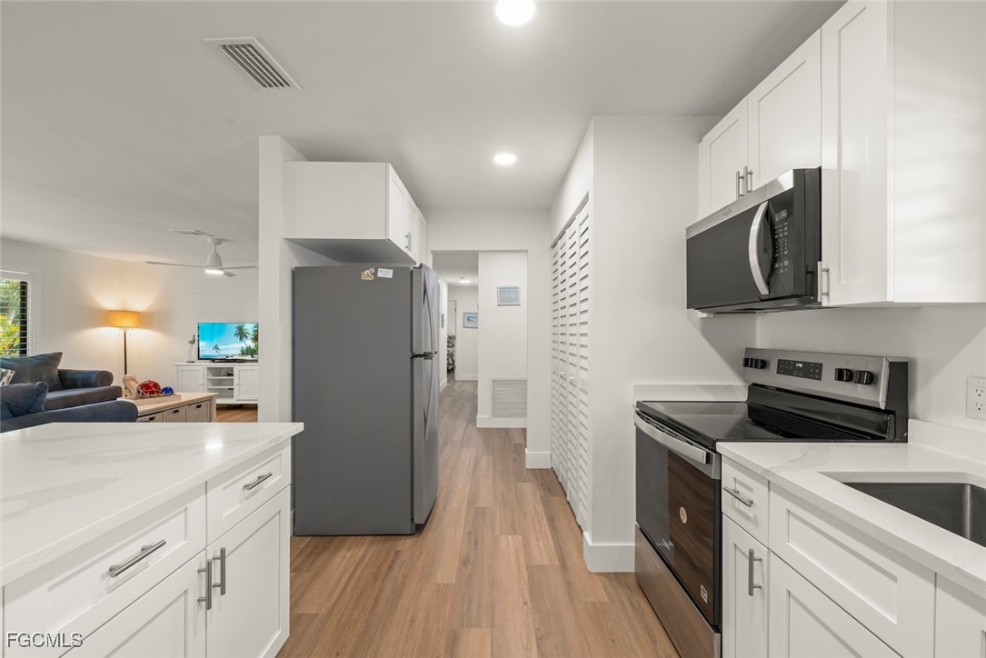 5117 Sea Bell Road, Unit D204 Sanibel, FL 33957 - Photo 18 of 48 a kitchen with a refrigerator a sink and a stove top oven with wooden floor